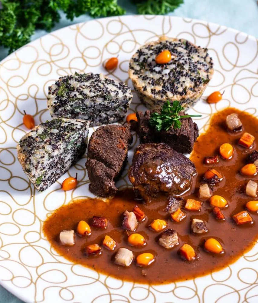 A plate of wild boar in sea buckthorn sauce with two quinoa and rice muffins