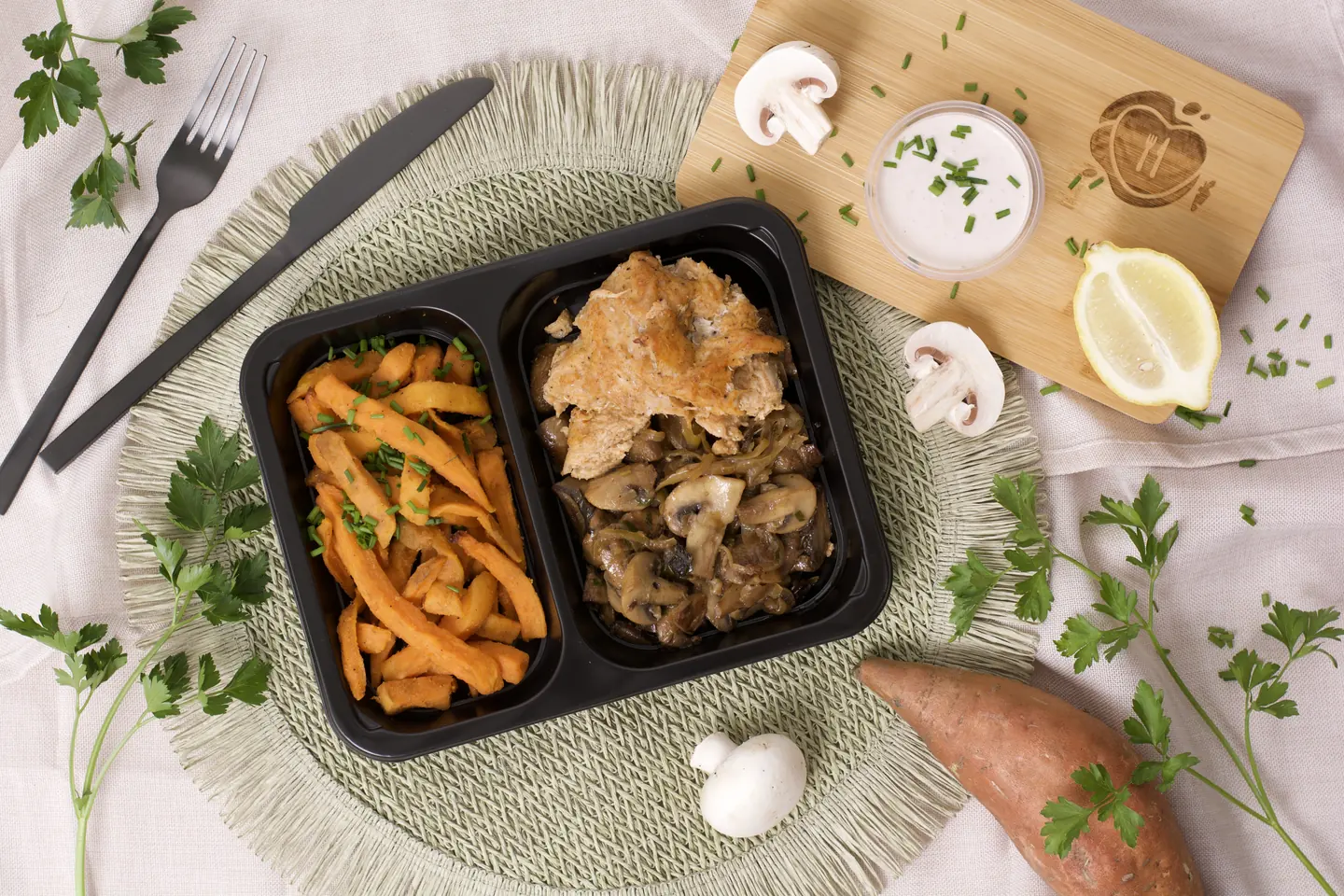 A meal box with breaded meat, sweet potato fries and mushroom sauce, shot from above